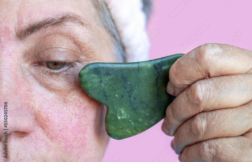 elder senior lady after 50 years old woman doing facial massage gua sha