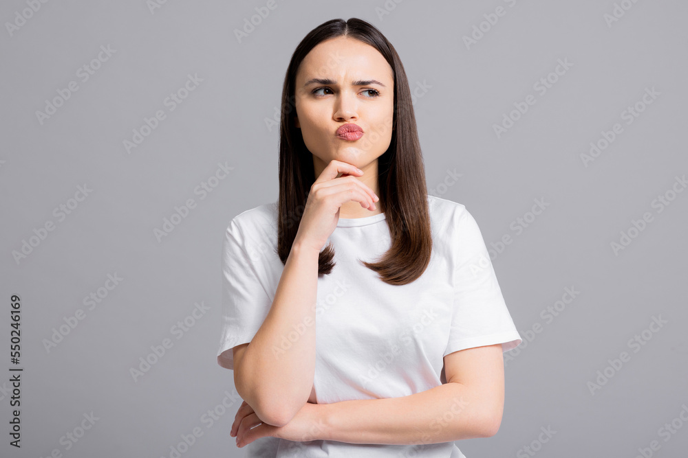 Portrait of beautiful thoughtful woman girl in doubt who stands on grey background wall with copy space shows different emotions isolated. Portrait of beautiful thoughtful woman girl in doubt who stands on grey background wall with copy space shows different emotions isolated.