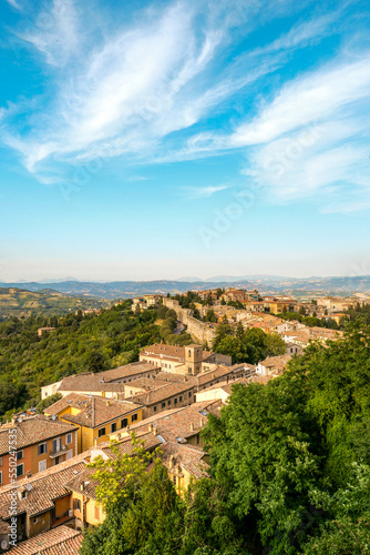 The view from above of the city, you can see the mountains and the roofs of the houses. Sun houses and tree tops seen from below.