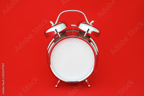 chrome retro alarm clock isolated on red background with empty clock face without hands and numbers