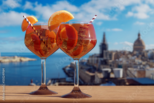 Two glasses of Spritz cocktail with view of Valletta harbor and old town in Valletta, Malta.