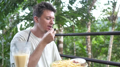 A man enjoying unhealthy food eating french fries and drinking sweet fruitshake. photo