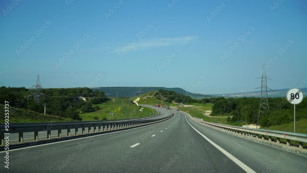 View from behind the car. The car drives along the road along the forest and green hills. Moving scenery. Road trip, trip to another city View from behind the car. The car drives along the road along the forest and green hills. Moving scenery. Road trip, trip to another city