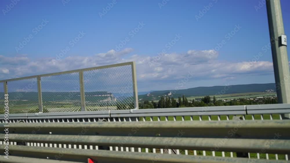 View from behind the car. The car drives along the road along the forest and green hills. Moving scenery. Road trip, trip to another city View from behind the car. The car drives along the road along the forest and green hills. Moving scenery. Road trip, trip to another city