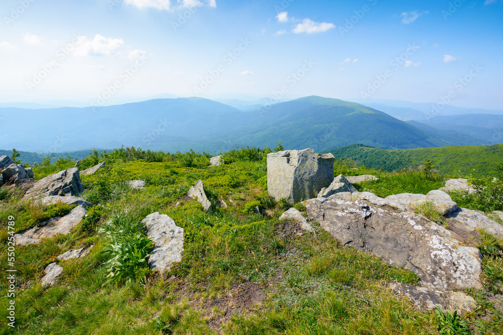 carpathian countryside in summer. mountain landscape with view in to the distant ridge and alpine valley. stones on the grassy meadow in the afternoon light