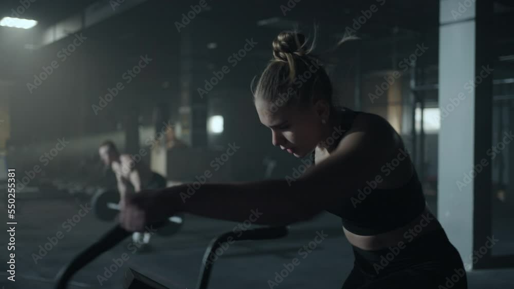 people in gym, woman is training hard on exercise bicycle in fitness hall, portrait of tired athlete people in gym, woman is training hard on exercise bicycle in fitness hall, portrait of tired athlete