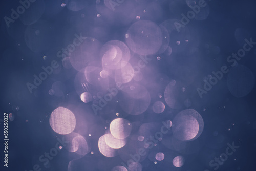 Blurred snowflakes in evening light at sunset. Colorful glowing bokeh abstract background.
