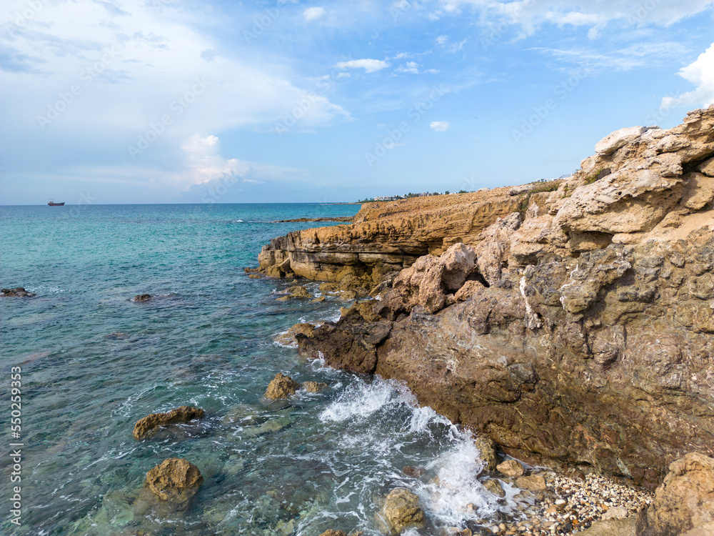 Coastal cliffs off the southern coast of Cyprus. Sea caves on the surf line. Coast of the Mediterranean Sea in the suburbs of Paphos.