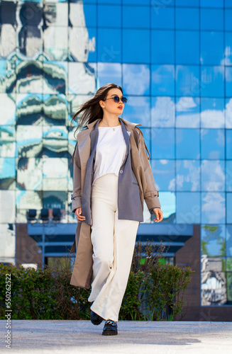 Portrait of a young beautiful brunette woman in blue jacket and white trousers photo