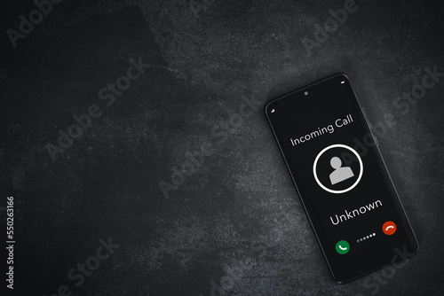 closeup smart phone screen with incoming call by unknown on rough grey background