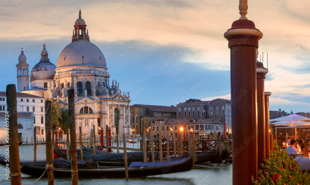 Venezia. Facciata della Salute sul Canal Grande con gondole e pali al crepuscolo
