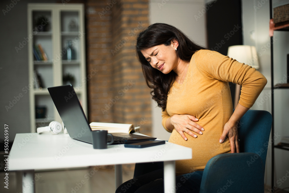 Young pregnant woman having painful contraction. Businesswoman holding her belly..