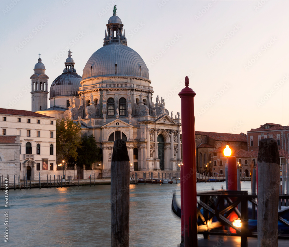 Venezia. Facciata della Salute sul Canal Grande con gondole e pali al crepuscolo