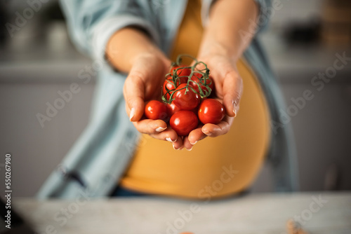 Valokuva Young woman in kitchen. Beautiful pregnant woman making salad