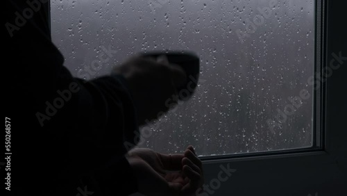 Man drinking warm drink near a window