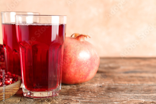 Glasses of fresh pomegranate juice on wooden table, closeup