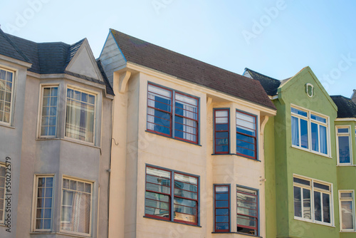 Row of modern house facades beige and green in late afternoon shade and blue and white gradient sky background