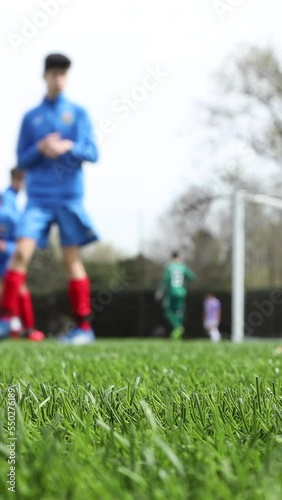 unrecognizable young soccer team training and doing workout routines, out of focus shot. vertical video for smart phone