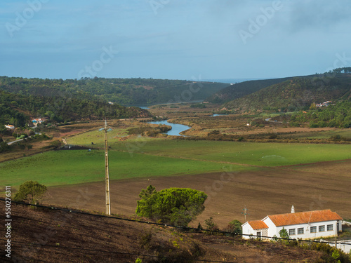 farm house, fields and green pastures with Rio Seixe river, forest and hills near Odeceixe, Portugal. Sunny day, blue sky. photo