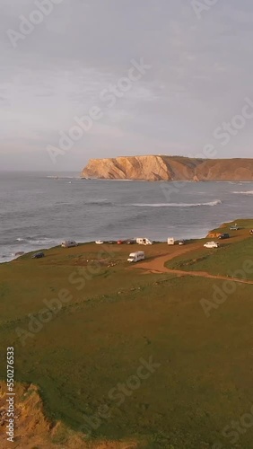 drone aerial view of the cliffs of Verdicio beach in Cantabria, an overnight stay area for camper vehicles, vertical video