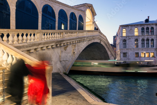 Venezia. Ponte di Rialto con persone e scia di vaporetto in transito sotto l'arco