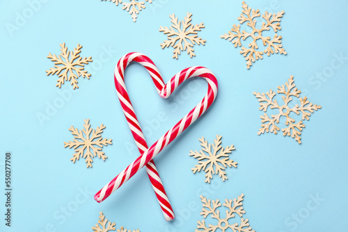 Heart made of candy canes and Christmas decorations on color background