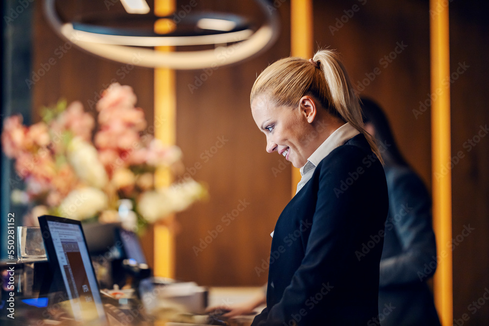 A receptionist is making an online reservation at a hotel reception. - obrazy, fototapety, plakaty 