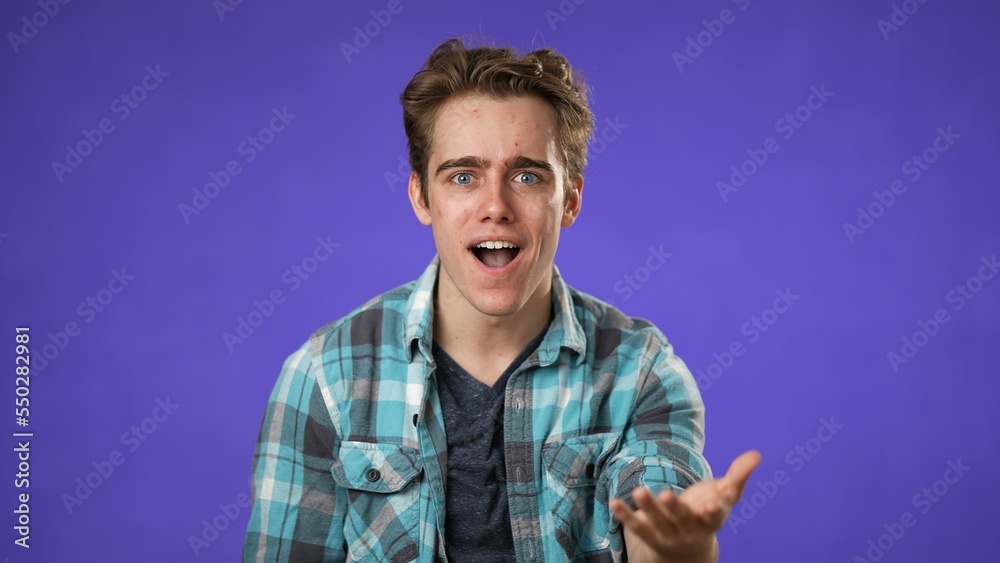 Obraz premium Portrait of amazed young man 20s shocked, saying WOW. Handsome guy surprised isolated on solid purple background.