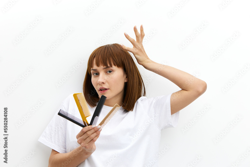a beautiful, pleasant woman with a beautiful hairstyle holds her hand above her head in a funny gesture, and in another comb. a beautiful, pleasant woman with a beautiful hairstyle holds her hand above her head in a funny gesture, and in another comb.