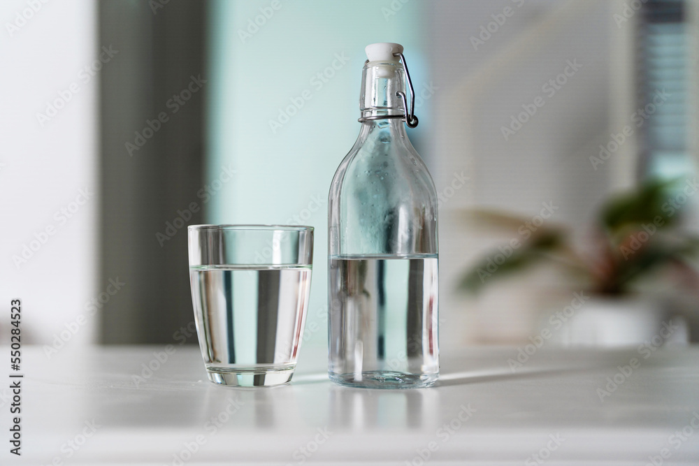 A glass of clean drinking water and a water bottle On a white wooden table A glass of clean drinking water and a water bottle On a white wooden table