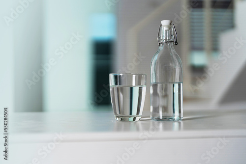 A glass of clean drinking water and a water bottle On a white wooden table