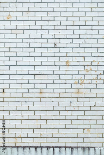 White brick wall. White bricks with many marks, cracks and discoloration from the elements. Exposed brick wall. White colored bricks