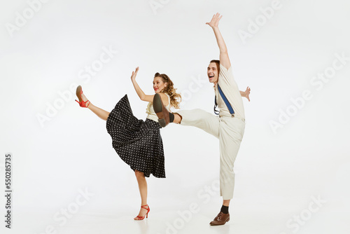 Young excited man and woman in 60s american fashion style clothes dancing retro dance isolated on white background. Music, energy, happiness, mood, action photo