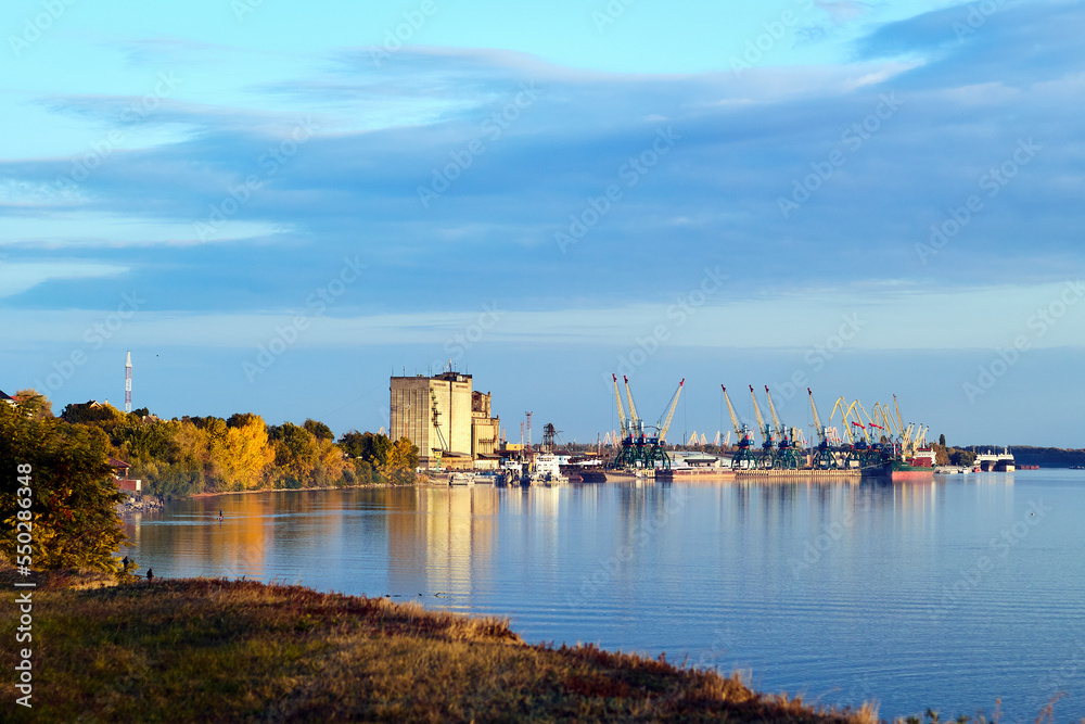 Port cranes and ships on port at the bank of Danube river