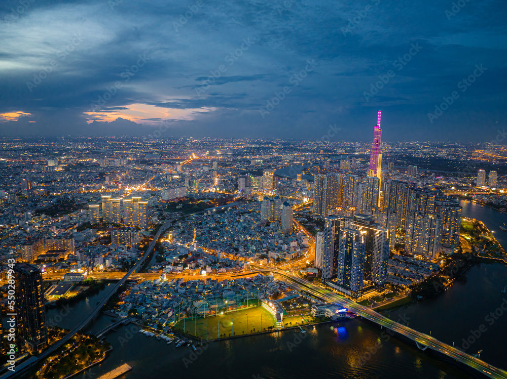 Naklejka premium Top view aerial photo from flying drone of a Ho Chi Minh City with development buildings, transportation, energy power infrastructure. Financial and business centers in developed Vietnam.
