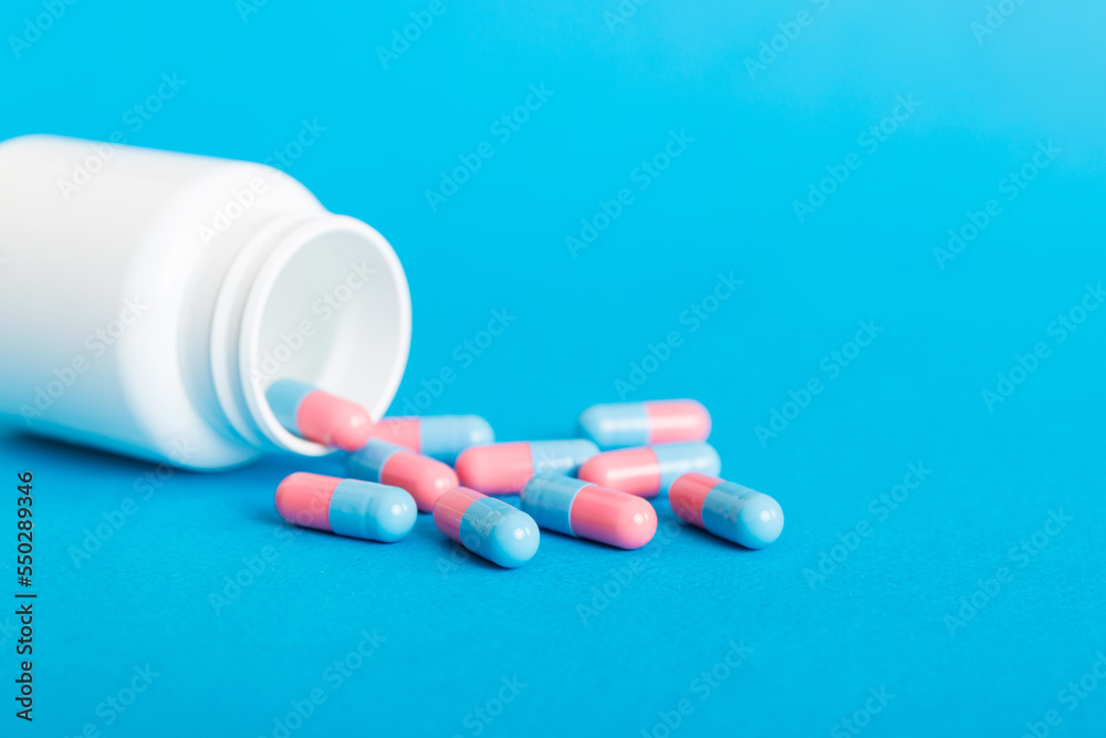 plastic medicine bottle with capsules of pills on colored background. Online pharmacy. Painkiller medicine and antibiotic drug resistance concept. Pharmaceutical industry