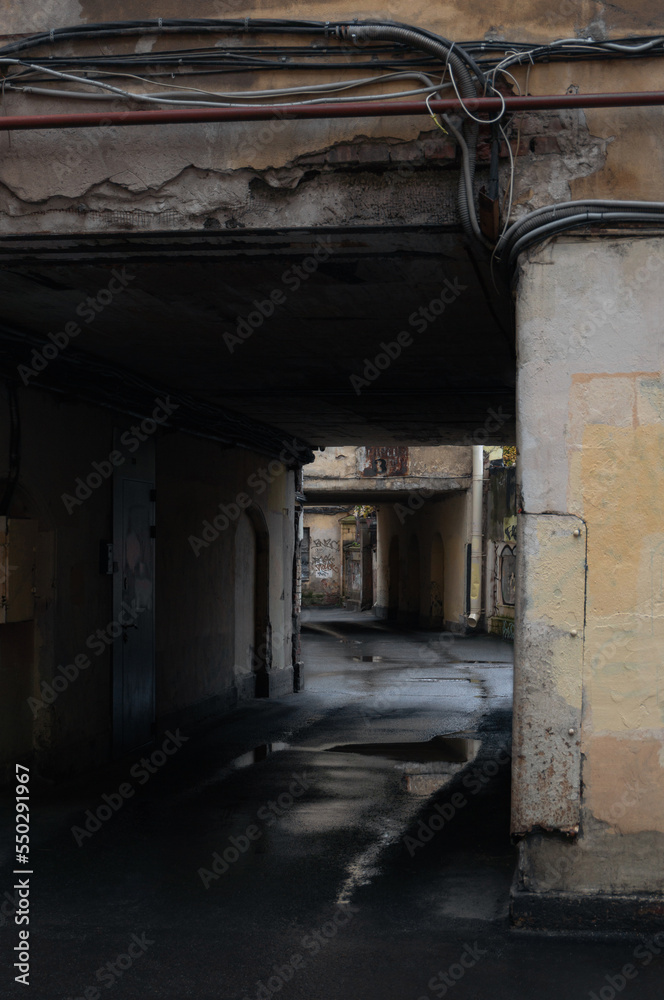 passage in the arch of the yellow house. a puddle on the asphalt. courtyard in St. Petersburg, Russia