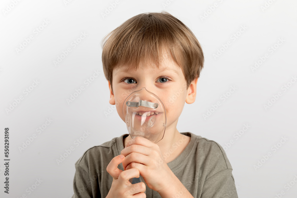 A boy with asthma does inhalations on a light background A boy with asthma does inhalations on a light background