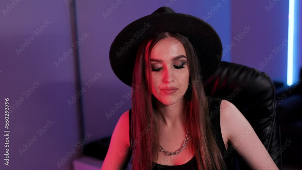 Beautiful musician woman in hat sings and plays the synthesizer at the same time in recording studio. Music production studio concept. Close up view Beautiful musician woman in hat sings and plays the synthesizer at the same time in recording studio. Music production studio concept. Close up view