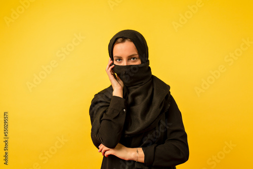 Indoor photo of eastern woman wearing black clothes looking aside with great smile on isolated yellow background