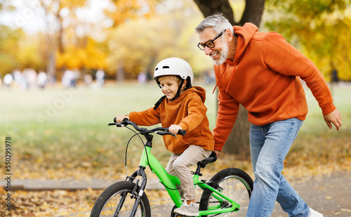 Happy family grandfather teaches child grandson  to ride a bike in park © JenkoAtaman