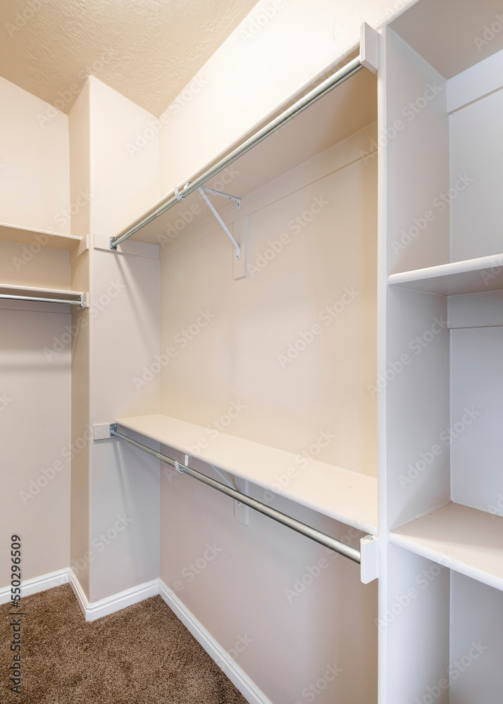 Vertical Narrow windowless walk-in closet with shelves and metal rods Vertical Narrow windowless walk-in closet with shelves and metal rods