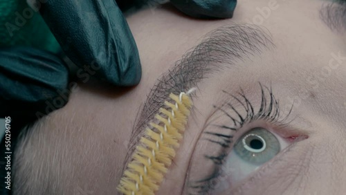 Eyebrow master shows the result of microblading work, moving the hairs of the eyebrow with a brush.