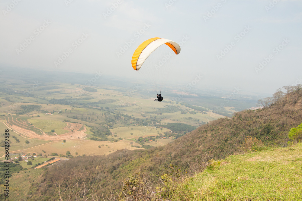 man flying a paraglider in a natural landscape man flying a paraglider in a natural landscape
