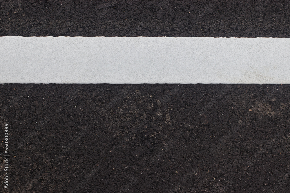White paint line on asphalt road surface, with gray color guidel