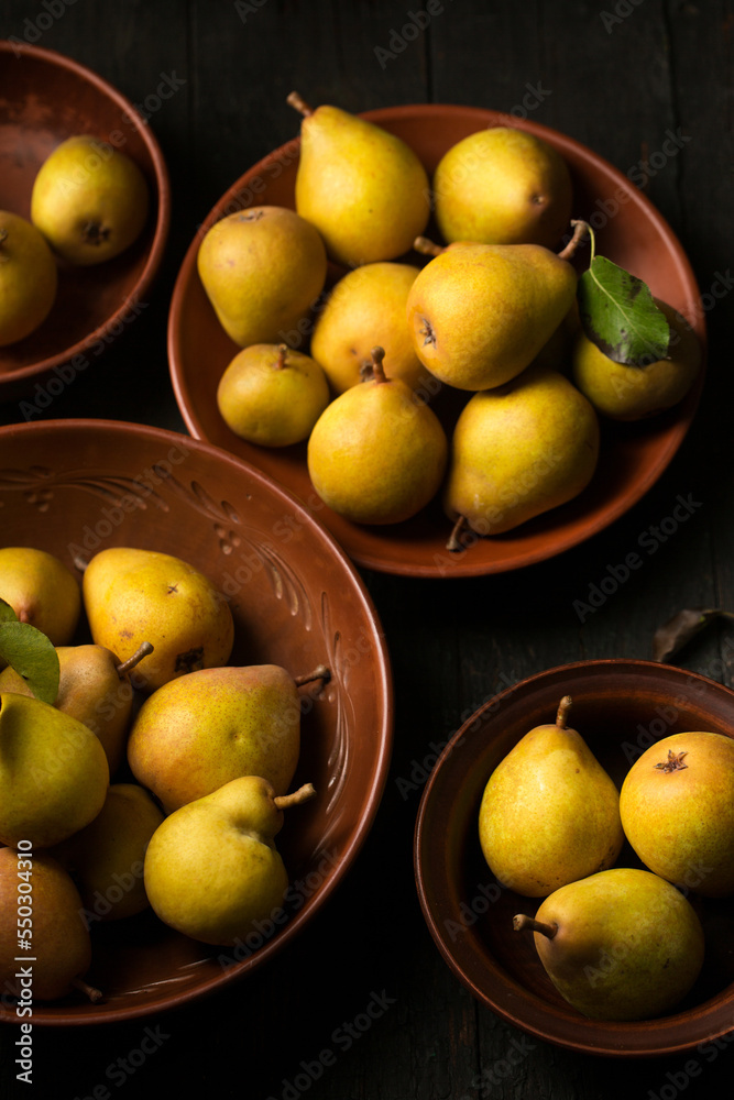 juicy pears in ceramic bowls on a dark background
