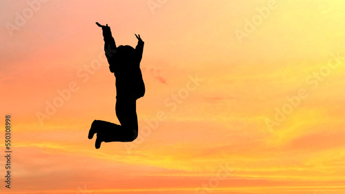夕焼けにジャンプする女性のシルエット_ワイド © smile