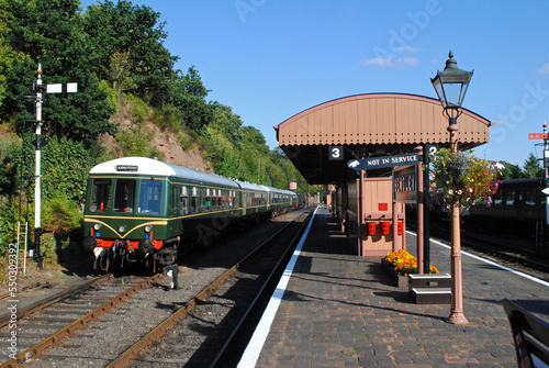 Covered Railway Station Platform with Vintage Diesel Rail Car and Semaphore Signal on Sunny Day 