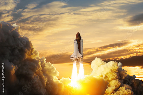 Fototapeta Naklejka Na Ścianę i Meble -  Spaceship lift off. Space shuttle with smoke and blast takes off into space on a background of sunset. Successful start of a space mission. Elements of this image furnished by NASA.