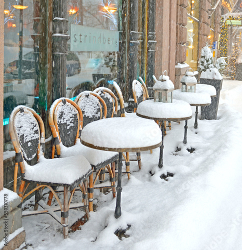 Snowfall and blizzard in Helsinki. Snow-covered tables of street cafe in Pohjoisesplanadi street in Christmas and New Year photo